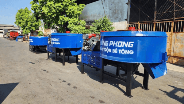 Ba máy trộn bê tông cưỡng bức màu xanh thương hiệu Đông Phong xếp hàng ngoài trời tại công trình
