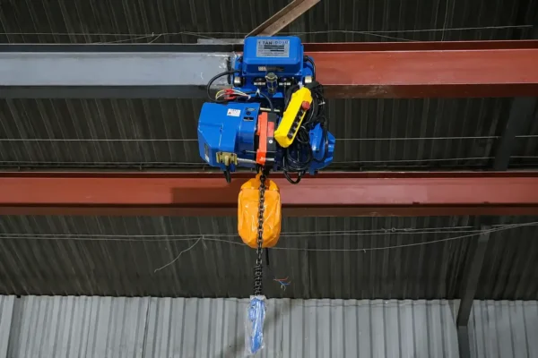 Pa lăng xích điện màu xanh 1 tấn treo trên dầm thép đỏ trong nhà xưởng