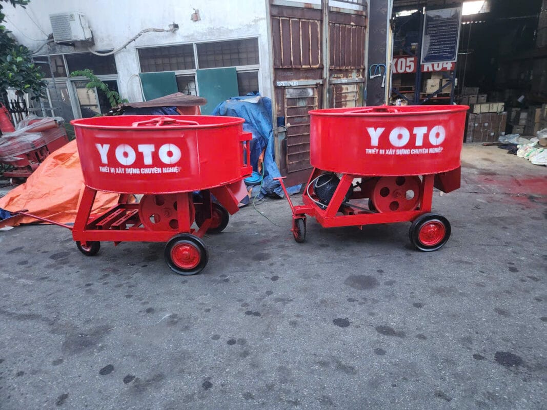 Máy trộn cưỡng bức bánh răng YOTO 350 – 500 Lít: Có Gì Khác? 4 Hai máy trộn bê tông thương hiệu YOTO màu đỏ đặt trước kho