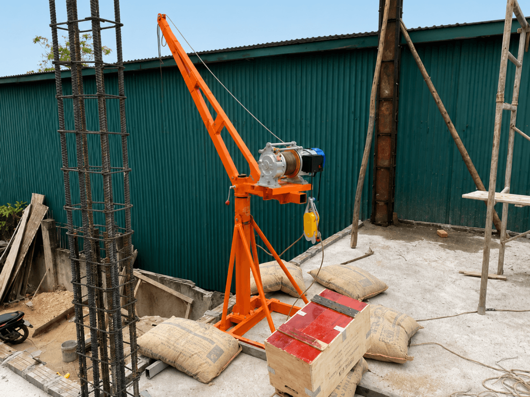 Tời điện màu cam tại công trường xây dựng với cốt thép và bao xi măng